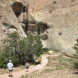 Visitors walking on a path near a cliff face
