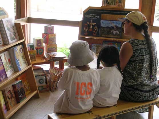 Image of kids and woman looking at children's books at the kid's corner in the visitor center