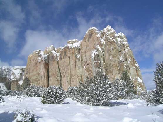 Sandstone cliff rises from a snowy field