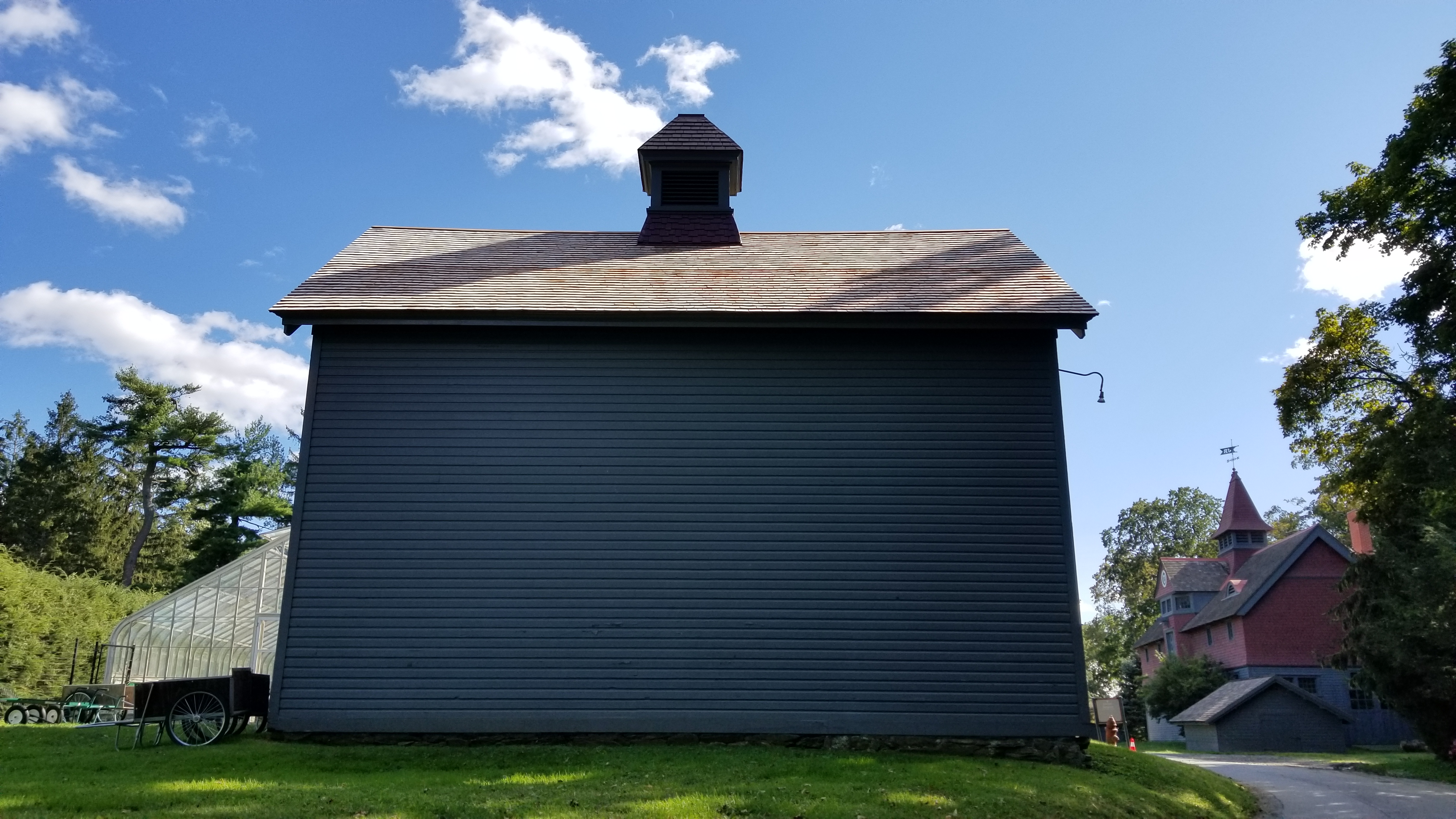 A wooden building, painted gray and red with a slanted roof with fresh shingles