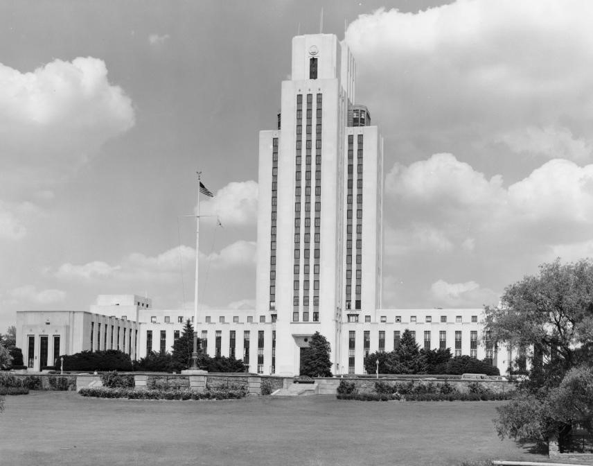 A building with a central tower and landscaping in front.