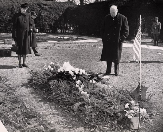 A man and a woman stand at a gravesite