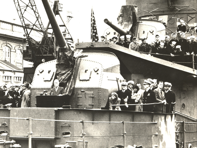 FDR Gives a Speech at Bremerton Navy Yard A crowd of people gathers at the front of a military ship to listen to one make speak from a podium