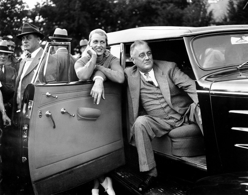 President Roosevelt and His Daughter, Anna A man sits in the passenger seat of a car, with the door open. A woman leans on the open car door.