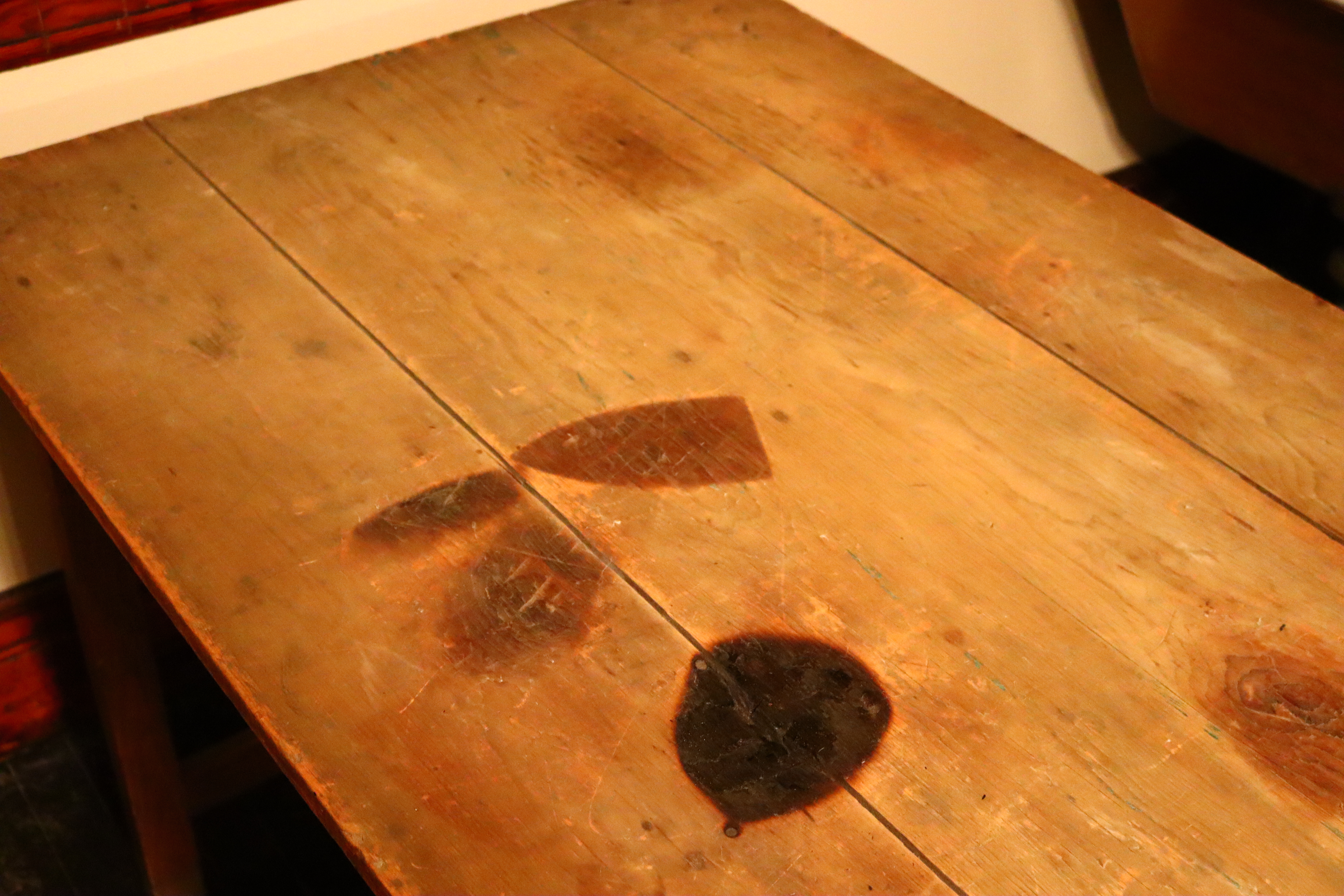 A wooden table with a scorch mark in the shape of a clothing iron.
