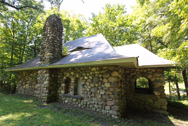 A one story stone building in a wooded setting