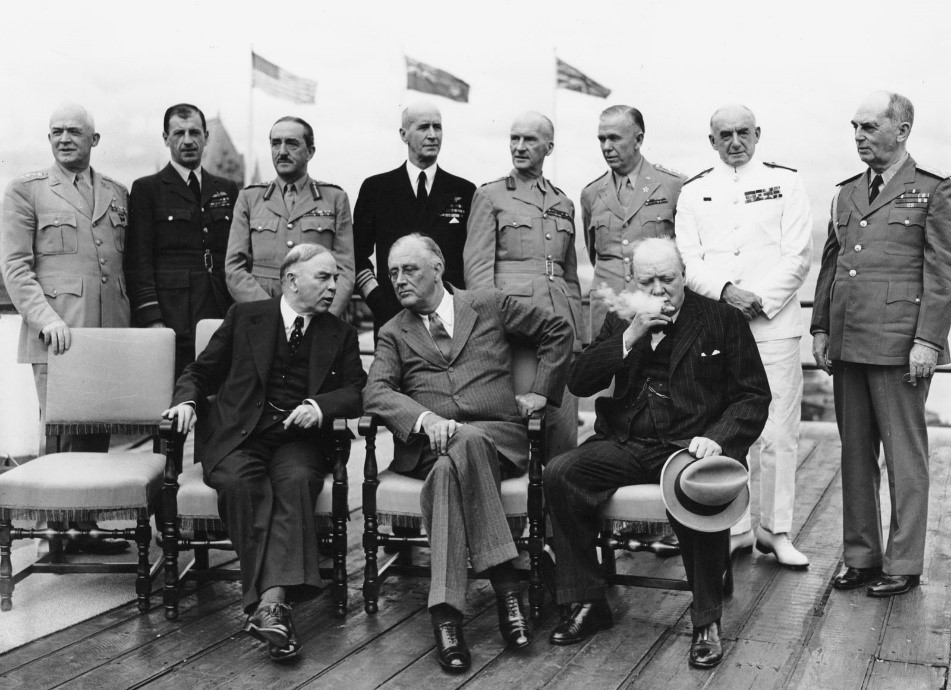 A group of men pose for a picture. Some are seated, others are standing