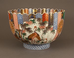 A porcelain bowl decorated with multicolored patterns, birds, and tropical plants.