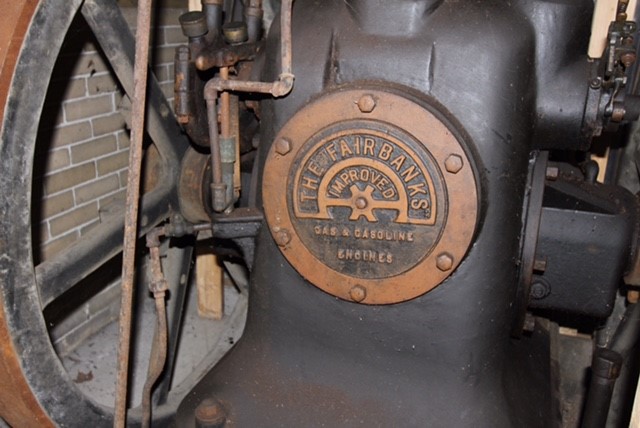 Close up image of a black antique motor. Gold insignia on the front reads 