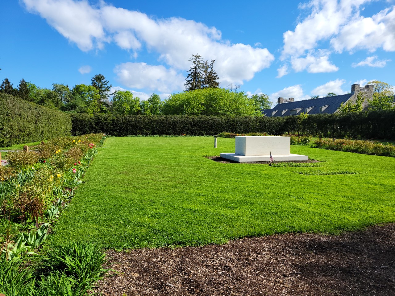 A marble monument surrounded by green space and a garden