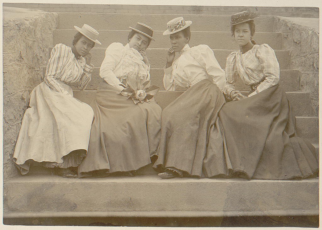 A group of women sitting on stairs, wearing shirtwaist ensembles of the 1890s