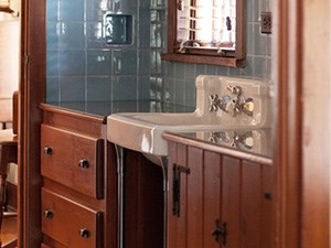 A bathroom sink surrounded by wood cabinets and ceramic tiles