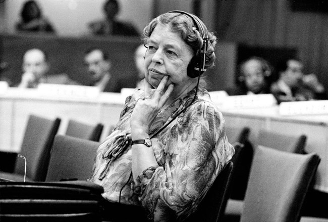 A woman seated at a desk wearing translator headphones.