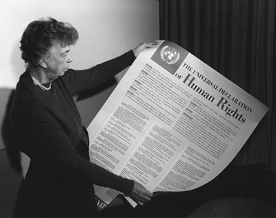 A woman holds a large printed version of the Universal Declaration of Human Rights.