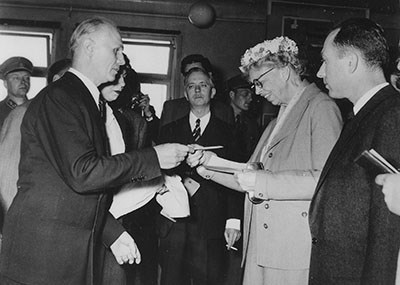 A women receives a document from a man while others look on.