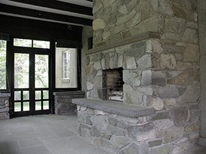 An enclosed porch with large stone fireplace.