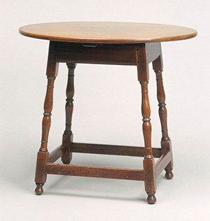 A wood table with four turned legs connected by stretchers at the base, with oval top.