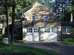 A two-story stucco building with gabled roof and a pair of double garage doors.