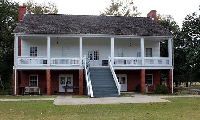 A large historic, two-story house, with a large veranda.