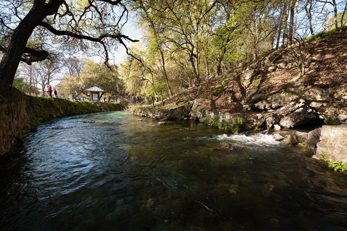 gorgeous dark blue spring with a tree hanging over it from the left and a brown hill on the right side gorgeous dark blue spring with a tree hanging over it from the left and a brown hill on the right side