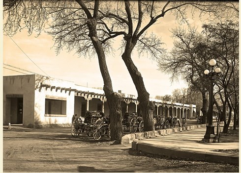 old photo showing wagons loaded with wood in front of Palace of the Governors