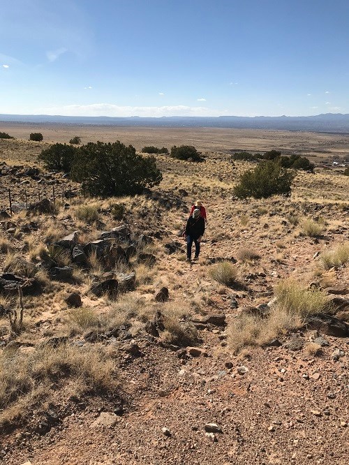 two people walking through a trail with rocks and dirt