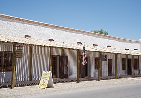 white spanish colonial building with wooden ceiling over the outside hall, and an american flag