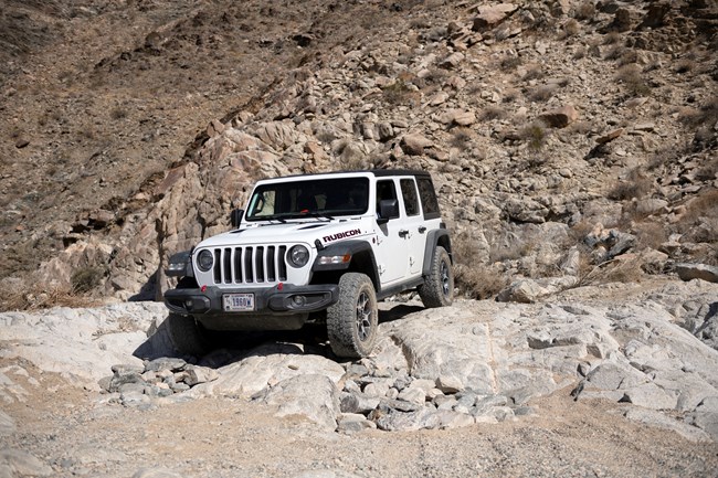 Un jeep se arrastra por una pendiente rocosa en medio de un desierto en una ruta designada.