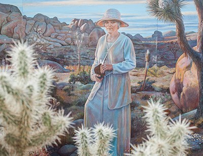 Un mural de una mujer en un paisaje desértico.