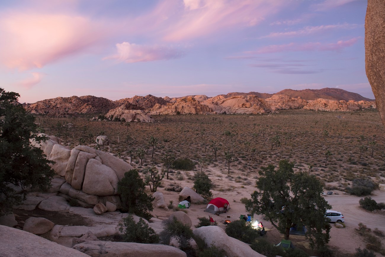 Un sitio de campamento con carpas alrededor de rocas de granito y el atardecer