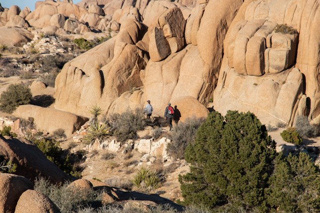 Dos excursionistas en un sendero entre grandes rocas.