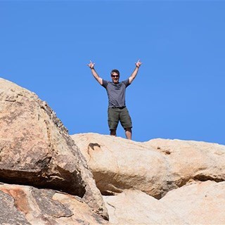 Un hombre parado en cima de una roca grande.