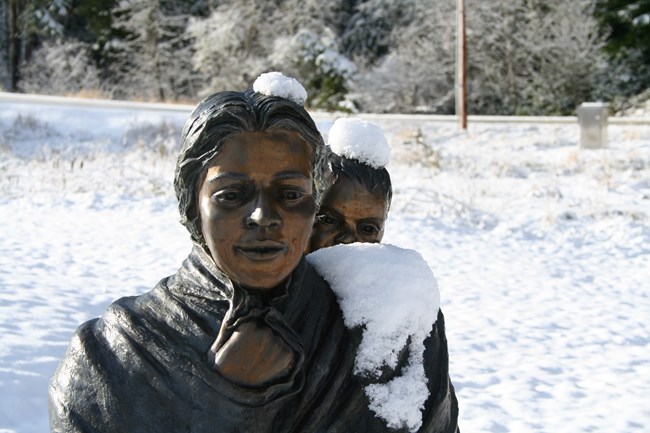 Bronze statue of Sacagawea with baby on her back in the snow