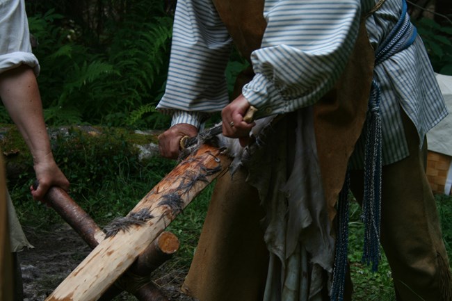 Dos manos raspando un piel de un venado con un cuchillo grande