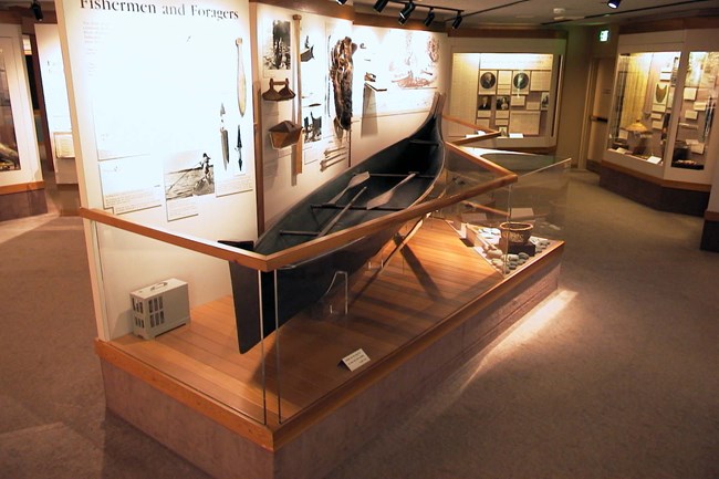Una canoa en una exhibición con las herramientas en la pared atras.