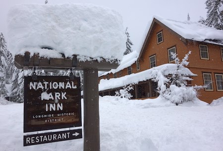 Cartel cubierto de nieve con la inscripción “National Park Inn” delante de un edificio.