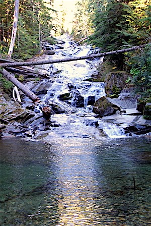 El agua cae sobre las superficies pulidas de rocas hacia el interior de un estanque.