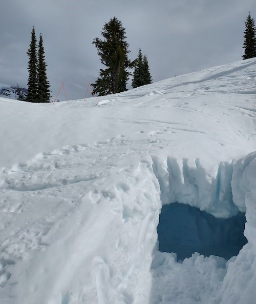 La entrada a una cueva de nieve excavada en el costado de una pendiente nevada.
