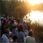 Students watch sunrise by a lake