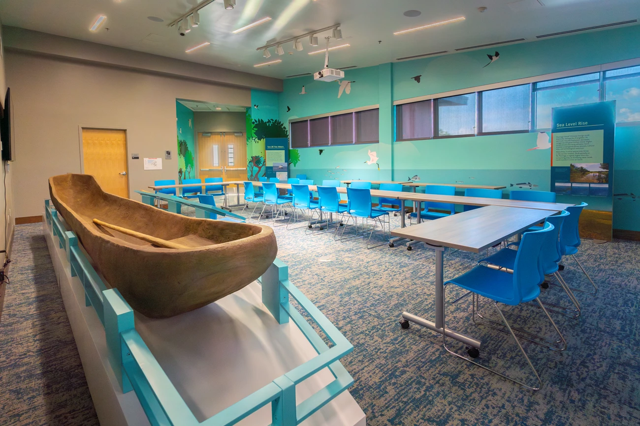 Multipurpose Room Meeting Large tables in a u-shape set up for a meeting in a room with decorative wallpaper and a replica canoe