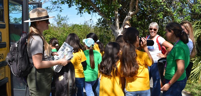 Ranger standing outside a bus with students and adults