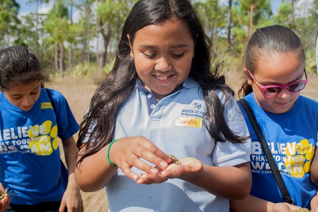 Female student smiling while holding small piece of algae