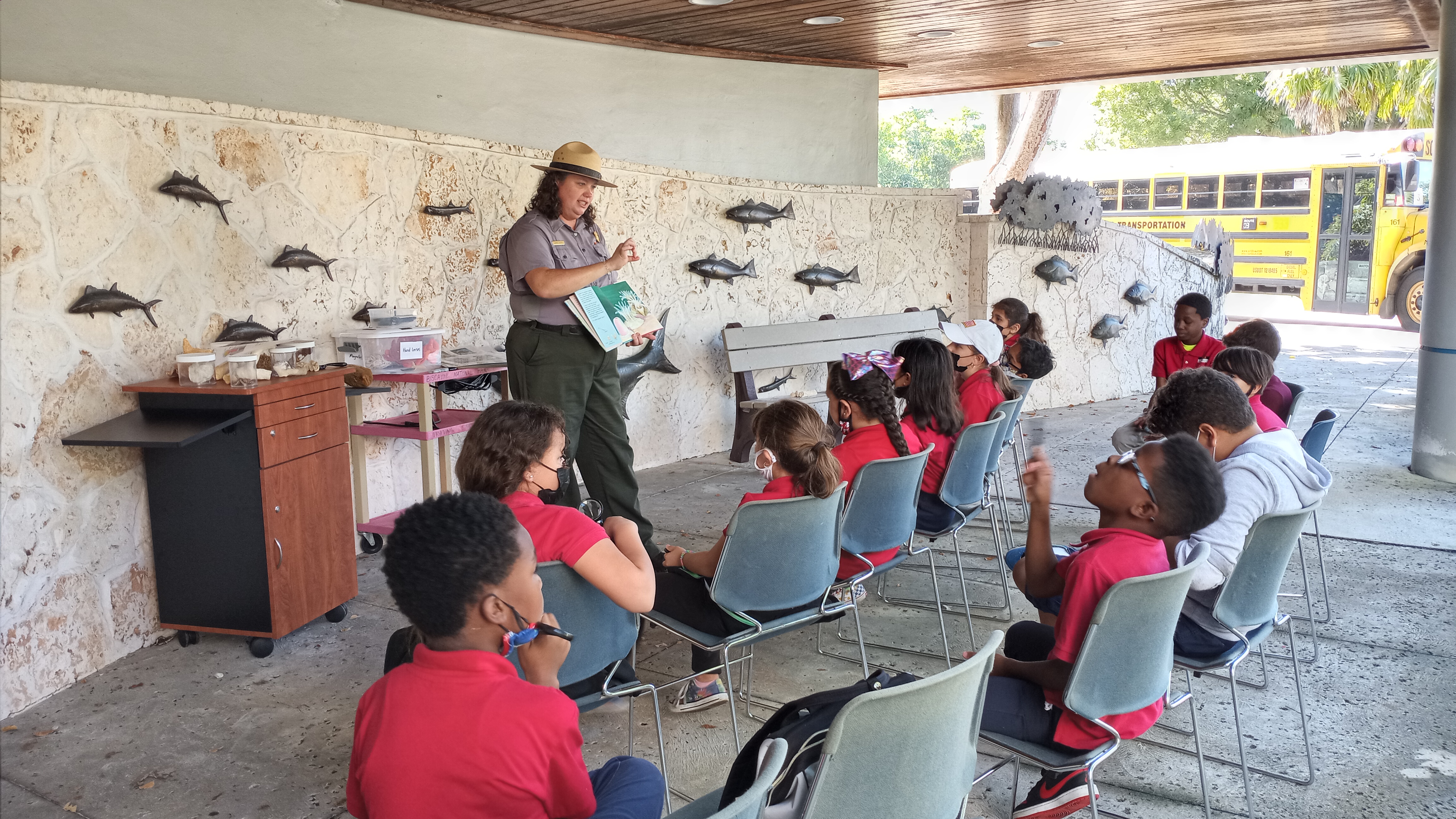 A ranger in uniform teaches a group of kids