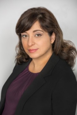 A portrait of a woman with long brown hair and brown eyes looking at the camera.