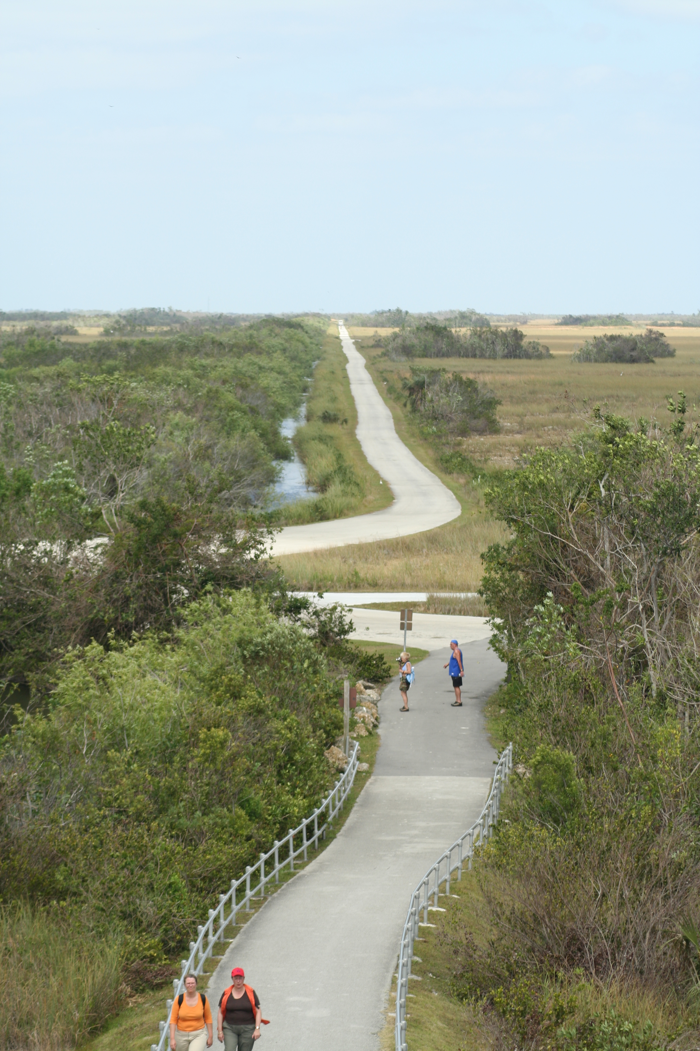 Aerial view of mostly straight paved road surrounded by grass and trees