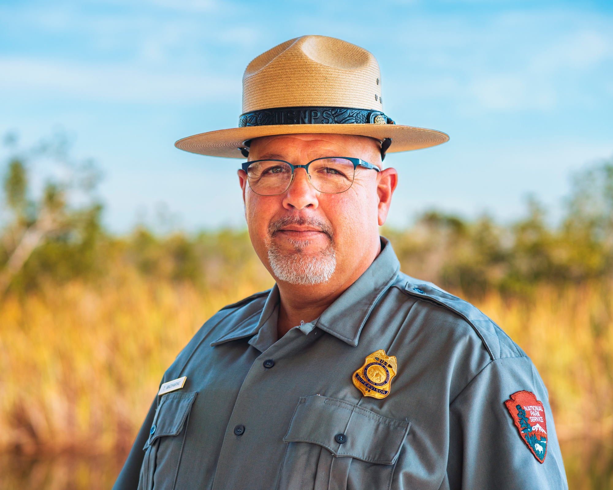 Head shot of a male park ranger in uniform with classic ranger hat with wide-brim and dark band.
