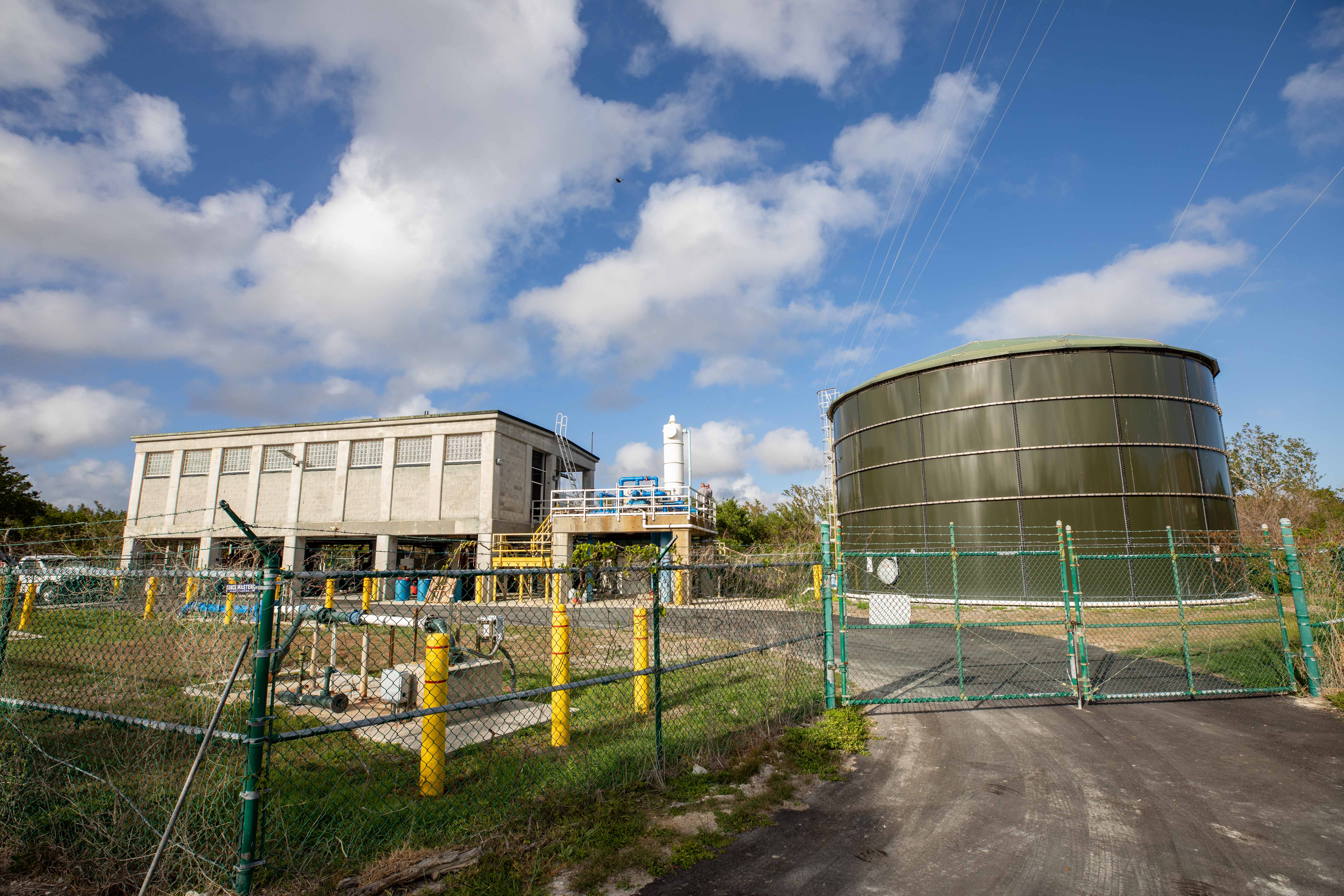 Flamingo Water Treatment Plant Large water tank, elevated concrete building and outdoor pipes behind a fence