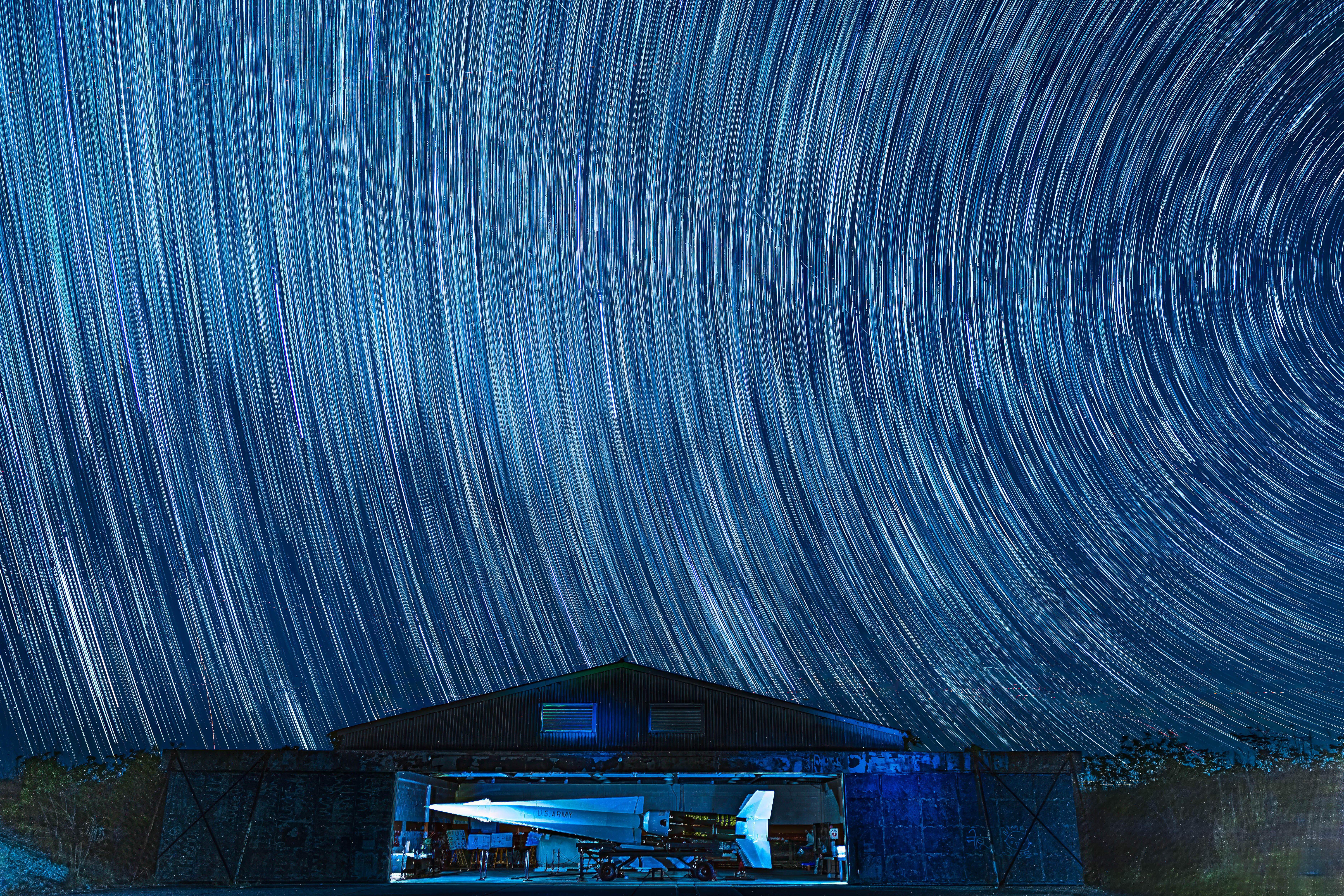 Image shows a large missile in a hangar at night under a sky full of stars.
