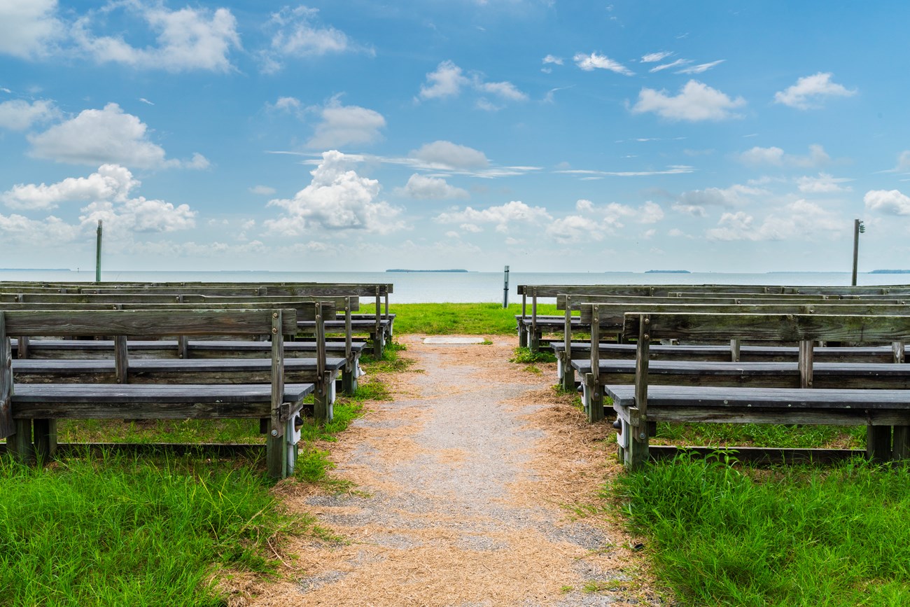 Wooden benches aligned in rows facing an ocean vista