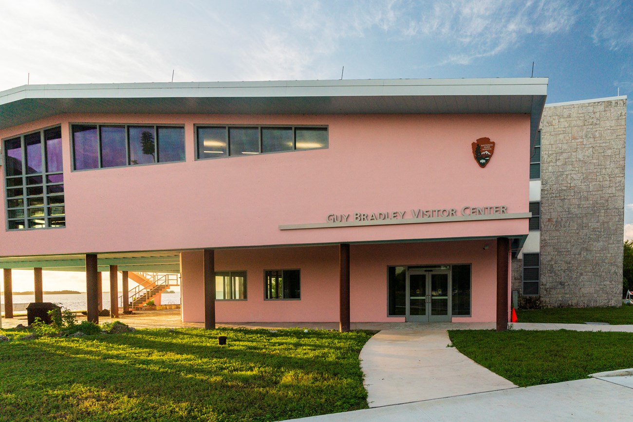 A large two-story pink building with "Guy Bradley Visitor Center" in large silver lettering
